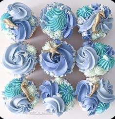 cupcakes decorated with blue and white frosting on a plate in the shape of sea animals