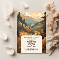 a wedding card with an image of mountains and trees on it, surrounded by flowers