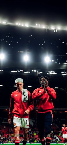 two soccer players walking on the field at night