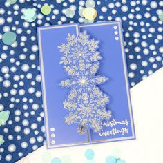 a blue and white snowflaked card on a polka dot tablecloth with confetti