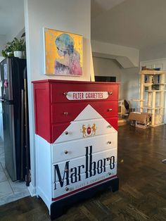 a red and white chest of drawers sitting on top of a hard wood floored floor