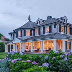 a large house with lots of windows and flowers in the front yard at night time