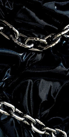 a black bag with silver chains hanging from it's sides and the bottom part of the bag