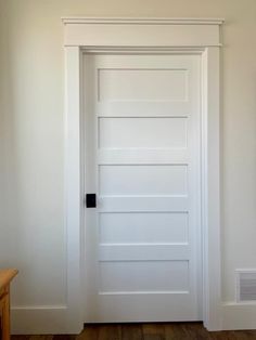 an empty room with a white door and wooden floor