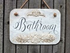 a bathroom sign hanging on the side of a wooden fence