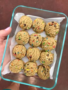 a person holding a glass container filled with cookies and sprinkles on top of it