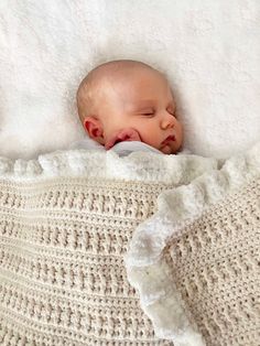 a baby sleeping on top of a white blanket