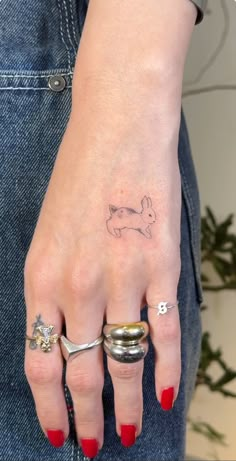 a woman's hand with two rings and a small tattoo on her left wrist