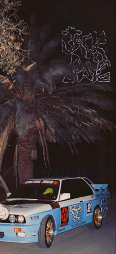 a car parked in front of a palm tree on the side of the road at night