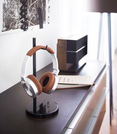 headphones are sitting on top of a black table in front of a painting and lamp