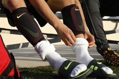 two soccer players tying their socks before a game