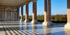 an empty room with columns and black and white checkered flooring on the ground