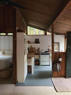 an open kitchen and living room area with wood paneling on the ceiling, white walls, and blue carpet