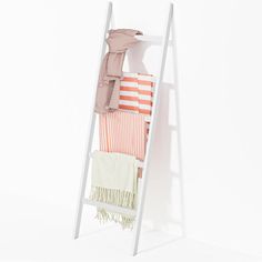 a white shelf with clothes and blankets hanging on it's sides, against a white background