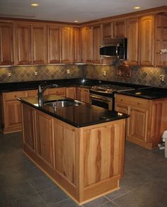 a kitchen with wooden cabinets and black counter tops in the middle of the flooring