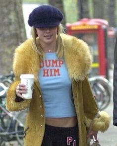 a woman walking down the street with a cup in her hand