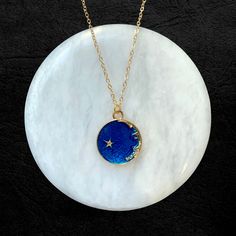 Gold-plated adjustable chain with dark blue ceramic night sky pendant. Available on a single chain as well as a double layered chain. Celestial Blue Necklaces, Celestial Blue Round Necklaces, Blue Celestial Round Necklaces, Blue Celestial Round Pendant Jewelry, Celestial Blue Round Pendant Jewelry, Celestial Blue Pendant Necklace, Adjustable Blue Moon-shaped Jewelry, Blue Moon Charm Pendant Necklace, Blue Celestial Pendant Jewelry