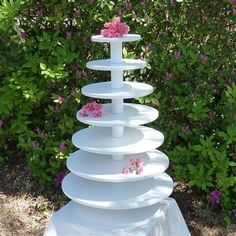 a tall white cake stand with pink flowers on top