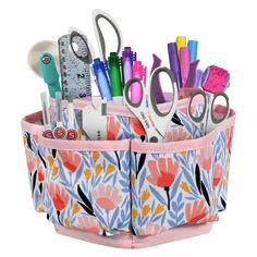 a pink and blue flowered pencil holder filled with scissors, markers, pens and other office supplies