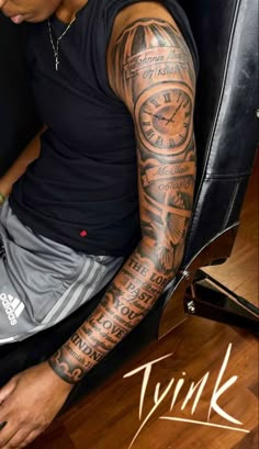 a man with tattoos on his arm sitting in a chair