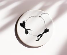 Rannka's black bow choker necklace effortlessly transitions from day to night, making it the perfect partner birthday gift for a romantic dinner. The sleek and modern black ribbon bow sits beautifully on a collarbone.  𝐒𝐈𝐙𝐄: ➤ Adjustable ➤ Fits Circumference from 12″ - 16″ (30cm - 40.6cm)  𝐃𝐄𝐓𝐀𝐈𝐋𝐒: ➤ Material: Stainless Steel, Black Ribbon Nickel Free, Lead-Free & Hypoallergenic, Non-Tarnish ➤ Ready to Ship ---- Black Bow Choker Necklace ---- -Featuring two black ribbon bows, both cla Bow Choker, Elegant Choker, Bow Necklace, Bow Jewelry, Romantic Dinner, Timeless Gifts, Romantic Dinners, Leather Bows, Necklace Black