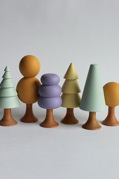 several small wooden trees are lined up against a white background with one standing out from the others