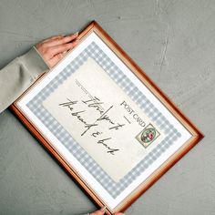 a person holding up a framed piece of paper