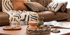 a coffee table with two vases and a book on it in front of a couch