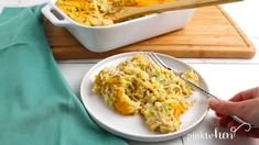 a white plate topped with chicken and rice casserole next to a wooden cutting board