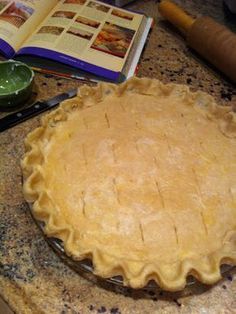 an uncooked pie sitting on top of a kitchen counter next to a book