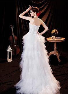 a woman in a white wedding dress standing next to a table with a violin on it