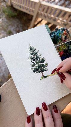 a woman's hands holding a piece of paper with a pine tree on it