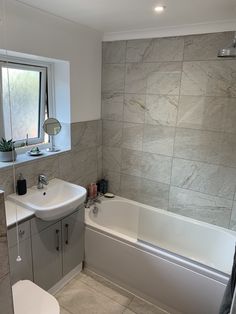 a bathroom with a sink, toilet and bathtub next to a window in it