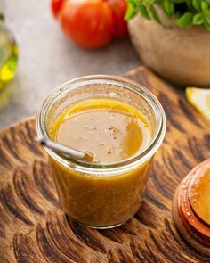 a jar filled with liquid sitting on top of a wooden cutting board next to sliced lemons and tomatoes