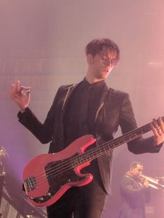 a man holding a red bass guitar on stage