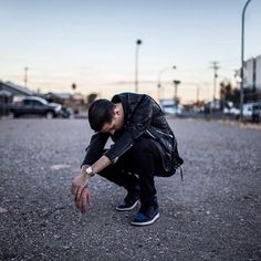 a man kneeling down in the middle of a parking lot with his hands on his knees