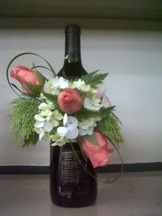 a wine bottle with flowers and greenery in it