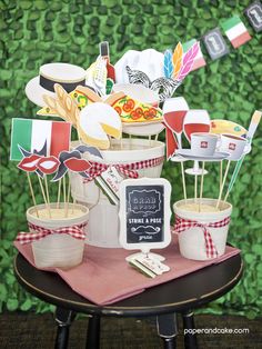 a table topped with cupcakes and cake toppers next to a green wall