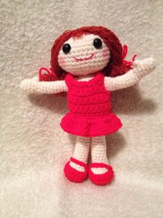 a crocheted doll with red hair wearing a pink dress