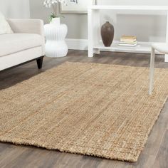 a living room area with white furniture and wood flooring, including a rug on the floor