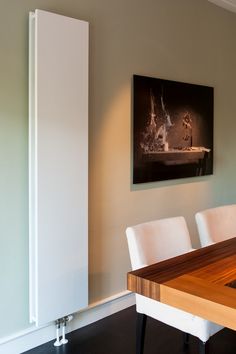 a dining room table with white chairs and a painting on the wall