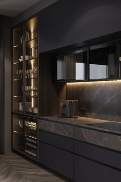 a modern kitchen with black cabinets and marble counter tops is lit by recessed lighting