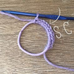 the crochet hook is being used to make a bracelet with two strands of yarn