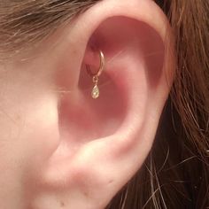 a woman's ear is shown with a single diamond in it, and there are two small diamonds on the side of the ear