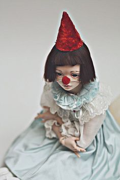 a doll dressed as a clown sitting on top of a bed