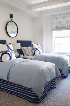 two beds in a bedroom with blue and white bedding