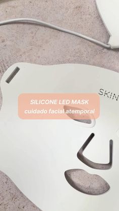 the face mask is white and has a pink label on it that says, silicone led mask cuidando faciale