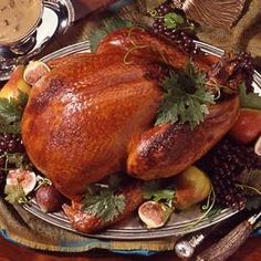 a roasted turkey on a platter with figs and grapes