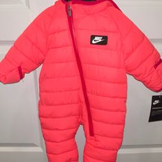 The Nike Snowsuit Provides An Outer Layer Of Lightweight Insulation To Help Little Ones Stay Warm When The Temperature Drops. Fold-Over Mittens And A Hood Offer Extra Coverage. Color: Racer Pink Benefits Lightweight Taffeta Is Smooth And Sturdy. Synthetic Fill Insulation Provides A Soft Layer Of Warmth To Keep Little Ones Cozy And Comfortable. Fold-Over Mittens Let You Adjust Their Level Of Coverage. Full-Length Zip Closure From Ankle To Chin Makes For Dressing Easy. Pinch Guards At The Chin Hel Nike Hooded Jacket With Double-lined Hood For Cold Weather, Pink Down Puffer Jacket With Detachable Hood, Nike Winter Jackets, Nike Puffer Jacket, Nike Coat, Grey Winter Coat, Infant Snowsuit, Soft Layer, Toddler Coat