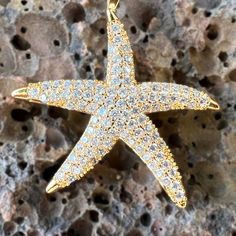 Get noticed with this sparkling 18K Gold Filled Large Star Fish Pendant. Each cubic zirconia is individually mounted to create an organic textured look with incredible shine. Each tip of the Star Fish has a polished finish further accenting the design. Includes 18K Gold Filled 3mm width, extra long 24 inch length Chain. 18K Gold Filled Star Fish Pendant Cubic Zirconia individually mounted Incredible shine and sparkle Polished tips accent the design Includes 18K Gold Filled 3mm width, extra long Gold Star Jewelry With Sparkling Stones, Star Shaped Cubic Zirconia Jewelry With Sparkling Stones, Gold Sparkling Star Jewelry, Cubic Zirconia Star Jewelry With Sparkling Stones, Gold Star-shaped Sparkling Jewelry, Gold Star-shaped Jewelry With Sparkling Stones, Elegant Pendant With Starfish Charm, Sparkling Gold Star-shaped Jewelry, Luxury Starfish-shaped Jewelry Gift